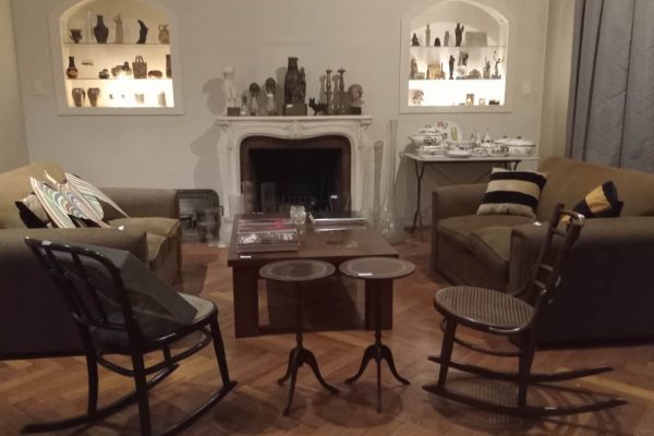 Par sofás 2 cuerpos; par silloncitos 1 cuerpo estilo Francés; pequeño diván capitoné; 2 sillas mecedoras Thonet;: sillón PC y otros plegable diseño, diseño cromado; mesas auxiliares: tapa vítrea, 3 planos en bronce y vidrio, 3 plegables, con patas torneadas; secretaire estilo Inglés con alzada vitrina, otro con tapa volcable y alzada vitrina; perchero estilo Inglés con espejo oval...