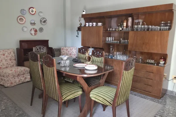 Sillón componible en 5 módulos, cuero color suela; par sillones 1 cuerpo; par butacas tapizadas en chenille floreado; 4 sillas tapizadas en eco cuero color uva; silla mecedora; sillas varias; mesas auxiliares: 3 niveles, en metal tapa vítrea, con galería en bronce, para TV, de fórmica y otras; comedor; mesa oval con tabla de alargue con 6 sillas tapizadas en pana rayada; mueble vajillero...