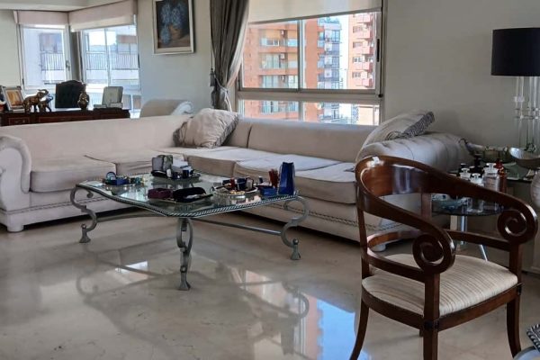 Mobiliario de la casa Wilson Tobal. Sillón en L componible tapizado gamuza sintética color arena con pasamanería y brazos en capitoné; chaise longue; par sillones 1 cuerpo respaldo curvo; silloncito respaldo curvo tapizado marrón; mesas auxiliares: tapa vítrea biselada y estructura hierro patinado forma irregular, tapa madera negra y estructura cromada, otras; consola con tapa de mármol y estructura en hierro, otra tapa mármol...